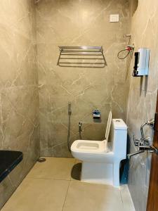 a bathroom with a toilet and a phone on the wall at Hotel Blue Petals in Shamshabad