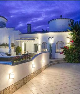 una gran casa blanca con piscina por la noche en Charmante villa avec piscine dans les canaux, en Empuriabrava