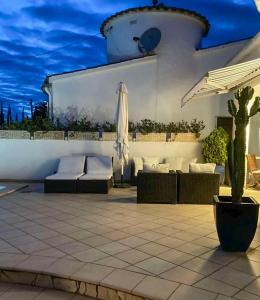 a patio with couches and an umbrella at Charmante villa avec piscine dans les canaux in Empuriabrava