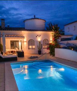 una piscina frente a una casa por la noche en Charmante villa avec piscine dans les canaux, en Empuriabrava