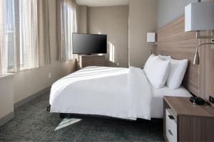 um quarto de hotel com uma cama branca e uma televisão de ecrã plano em TownePlace Suites by Marriott New York Brooklyn em Brooklyn