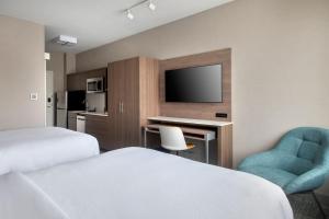 a hotel room with two beds and a desk and a tv at TownePlace Suites by Marriott New York Brooklyn in Brooklyn
