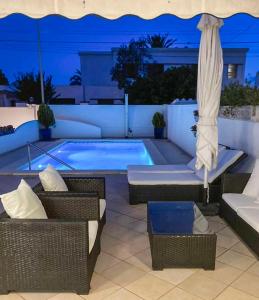 a pool with wicker chairs and a umbrella and a table at Charmante villa avec piscine dans les canaux in Empuriabrava