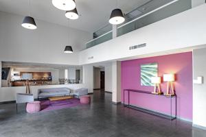 a lobby with pink and purple walls and a couch at City Express by Marriott Silao Aeropuerto in Silao