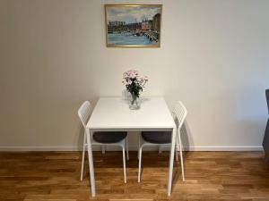 einen weißen Tisch mit Stühlen und eine Vase aus Blumen in der Unterkunft New apartment, perfect for exploring Stockholm in Lidingö
