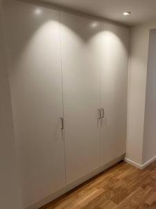 een witte kamer met witte kasten en een houten vloer bij New apartment, perfect for exploring Stockholm in Lidingö