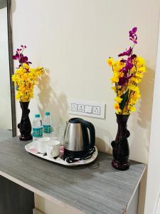 a table with two vases with flowers and a tea pot at Hotel Blue Petals in Shamshabad