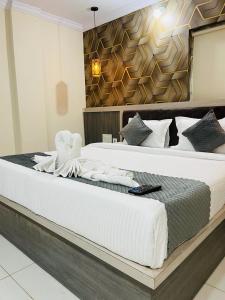 a bedroom with a large bed with white sheets at Hotel Blue Petals in Shamshabad