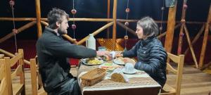 un hombre y una mujer sentados en una mesa comiendo comida en the wooden house choquequirao, en Cachora