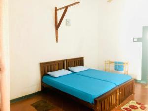 a bedroom with a bed with blue sheets and a cross on the wall at Kandyan Holiday Center in Kandy