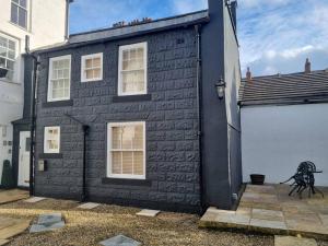 a black brick building with a white wall at Hidden Gem. 1800s Bank Office. Knaresborough Town in Knaresborough