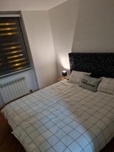 Un dormitorio con una cama blanca con una ventana. en Jenny's Place Sarajevo, en Sarajevo