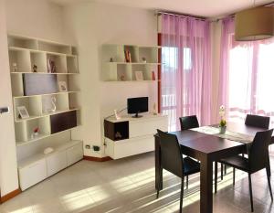 una sala da pranzo con tavolo, sedie e TV di la Dolce Vita - Appartamento con parcheggio privato vicino al centro e all'ospedale ad Asti