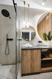 ein Bad mit einer Dusche und einem Waschbecken mit einem Spiegel in der Unterkunft Golden Dreams Luxury Apartments 21 in Krakau