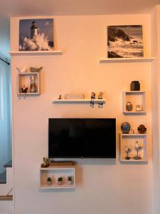 a flat screen tv on a wall with shelves at Villa Noroit in Cherrueix