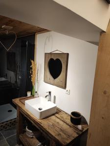 a bathroom with a white sink and a heart on the wall at Appartement Chez Marie et Aymeric in Bages