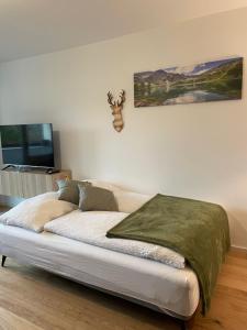 a bed in a living room with a tv on the wall at Wolfgangsee Ferienappartement „Almliebe“ in Strobl