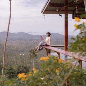 a woman sitting on the edge of a wooden deck at SZ Samui Glamping in Ban Sa Ket