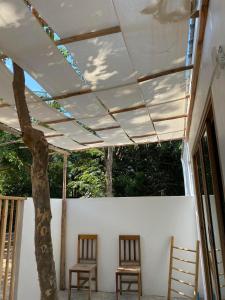 班克蘭的住宿－Tree nara garden houes kohlarn，两把椅子在门廊上遮篷下,有一棵树