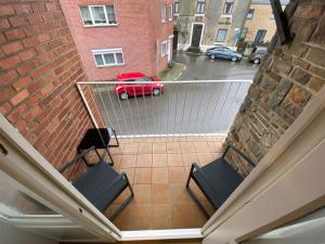 - un balcon avec deux chaises et une voiture rouge dans une rue dans l'établissement 012-Superbe étage spacieux avec balcon extérieur netflix gratuit, à Charleroi