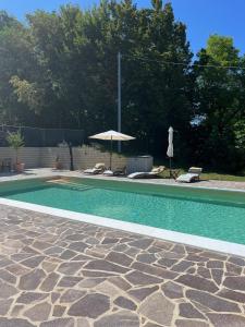 uma piscina com um guarda-sol e duas cadeiras e um guarda-sol em Casa Al Fondo em Gualdo di Macerata