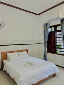 ein weißes Bett in einem Zimmer mit Fenster in der Unterkunft BeachSide House Mui Ne II in Ấp Khánh Phước (1)