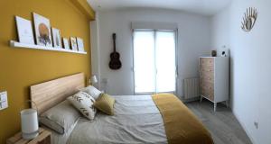 Piso acogedor y amplio en el centro de Tolosa في تولوسا: غرفة نوم بسرير وجدار اصفر