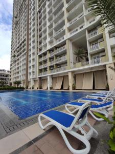 a swimming pool with lounge chairs in front of a building at SERENDIPITY PLACE @CELANDINE in Manila