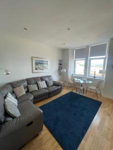 a living room with a couch and a blue rug at Millport Beach Apartment, Crichton St, sea views in Millport
