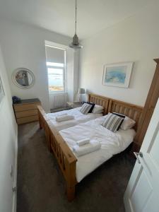 a bedroom with two beds with white sheets at Millport Beach Apartment, Crichton St, sea views in Millport