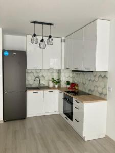 a kitchen with white cabinets and a black refrigerator at Apartament No 3 in Lublin