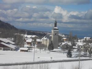 a snow covered town with a church with a tower at Studio cabine au cœur de la montagne Les Memises in Thollon