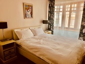 1 dormitorio con 1 cama blanca y ventana en Georgian Guest Rooms en Basilea