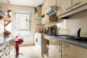 une cuisine avec un comptoir et un tabouret rouge dans l'établissement Charmant 3P. Calme, spacieux et lumineux. 90 m2, à Paris