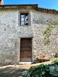 a stone building with a wooden door and a window at Tuscany Escape in Borgo a Mozzano