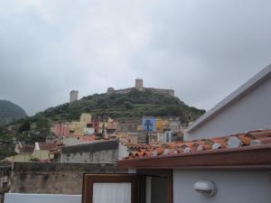 une colline avec un château au sommet d'une ville dans l'établissement Bomarosa B&B, à Bosa