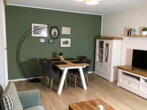 a dining room with a table and a green wall at Ferienwohnung am Steinsbach in Bad Berleburg