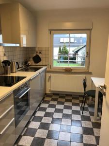 a kitchen with a checkered floor and a window at Ferienwohnung am Steinsbach in Bad Berleburg