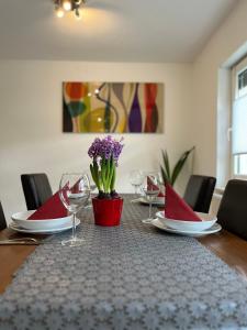 a table with plates and glasses and a vase with purple flowers at Beishan Appartements Nürnberg in Nürnberg