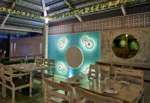 um restaurante com mesas e cadeiras e uma parede com pratos em Ramee Panchshil em Colhapur