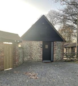 a brick house with a black door and a stone wall at The Studio in Climping in Climping