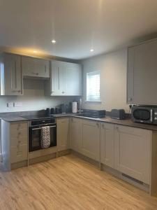 a kitchen with white cabinets and black appliances at The Studio in Climping in Climping