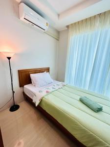 a bedroom with a bed with a lamp and a window at S303 Good Apartment Chalong Na-kok in Phuket Town