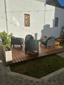 una terraza de madera con sillas y mesa en Lo de Carlos en Santa Teresita
