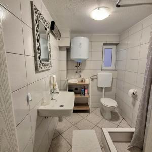 a white bathroom with a sink and a toilet at Apartment Kapetanovic in Bosanski Šamac