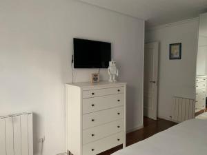 a bedroom with a dresser with a television on it at Apartamento en Liencres in Liencres