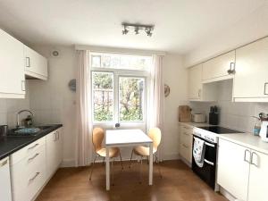 uma cozinha com mesa e cadeiras e uma janela em East Finchley N2 apartment close to Muswell Hill & Alexandra Palace with free parking on-site em Londres