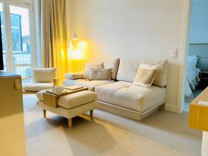 uma sala de estar com um sofá e uma cadeira em Villa Astoria - Suiten am Meer em Kühlungsborn