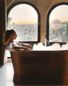 a woman in a bath tub in a train with a hot air balloon at Sultan Cave Suites in Göreme