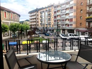 einen Balkon mit einem Tisch und Stühlen in einer Stadtstraße in der Unterkunft Piso acogedor y amplio en el centro de Tolosa in Tolosa